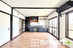 和の趣を感じさせる引き戸と、モダンなキッチン空間が調和する広々とした居住空間。木目の床が温かみと落ち着きをもたらし、採光窓からは心地よい明るさが空間を満たしています
